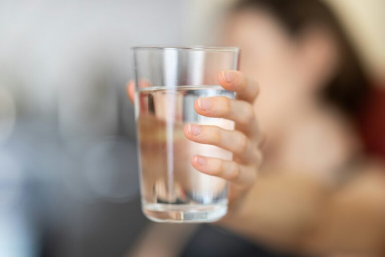 Hand hält Wasserglas