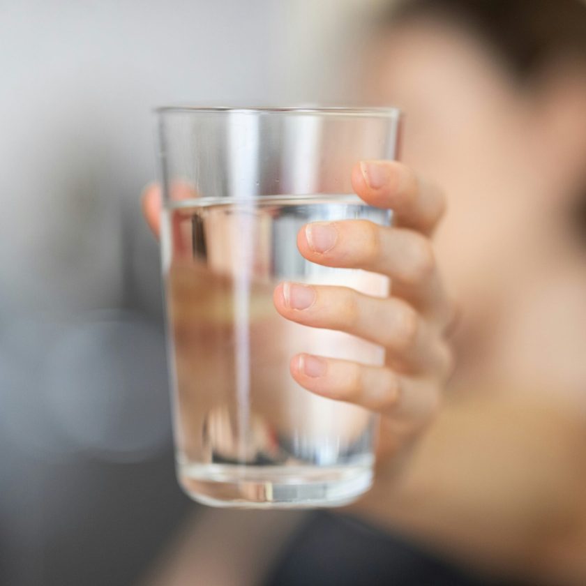 Hand hält Wasserglas